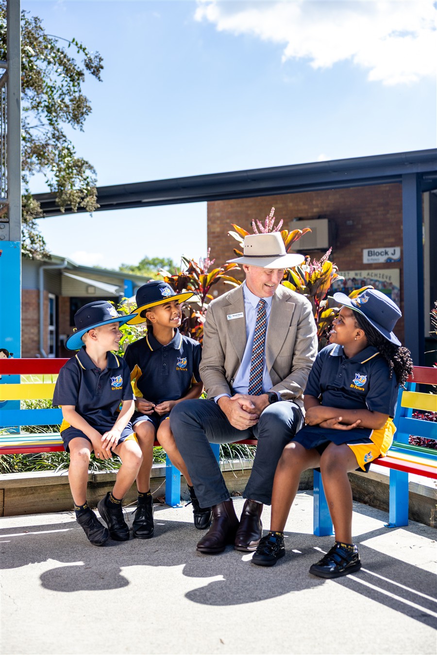 Principal sitting with students at buddy bench