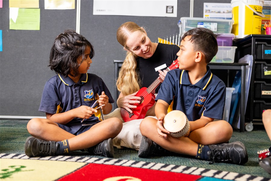 teacher sitting with students playing instruments