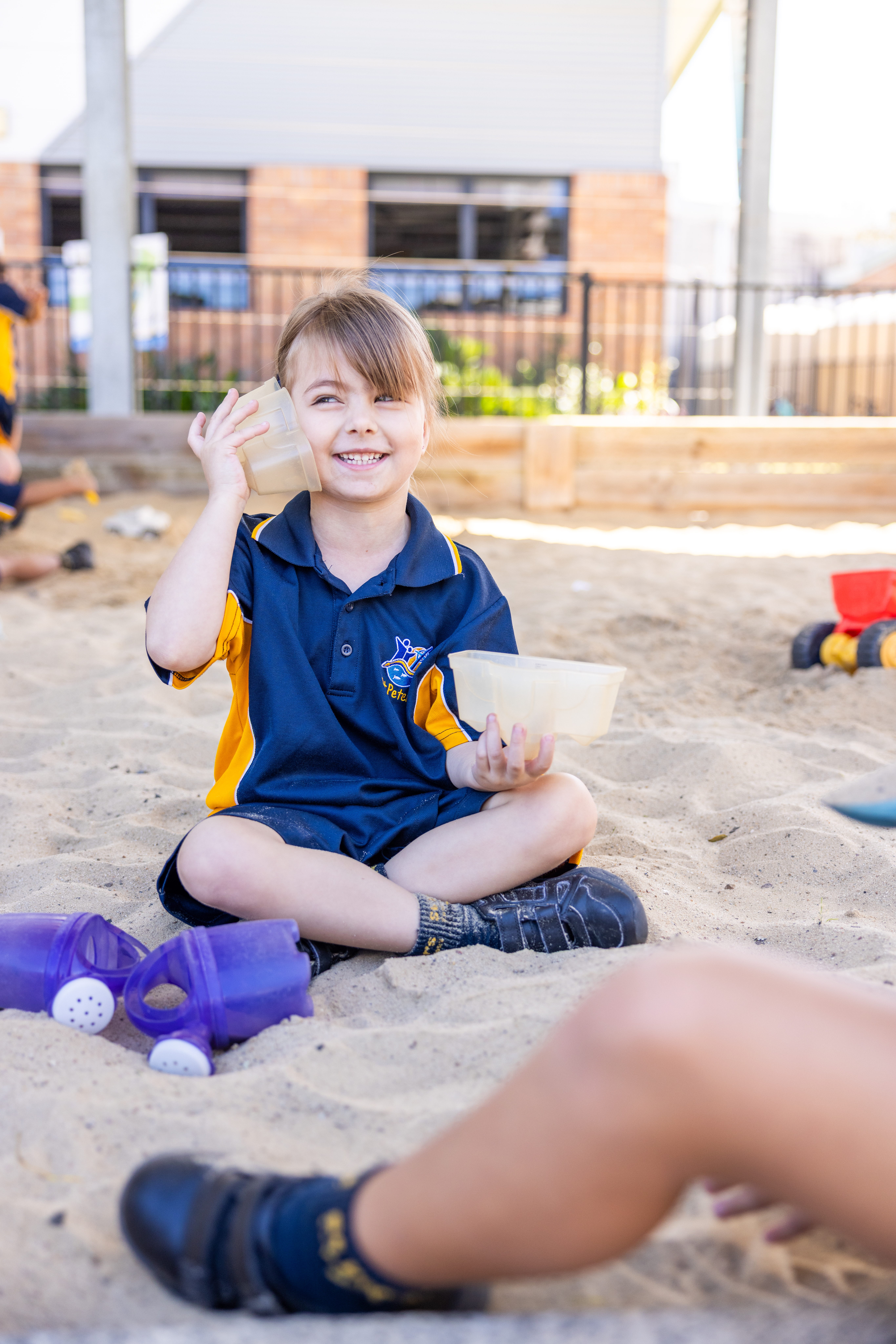 Prep student playing in sand pit pretending to be on the phone