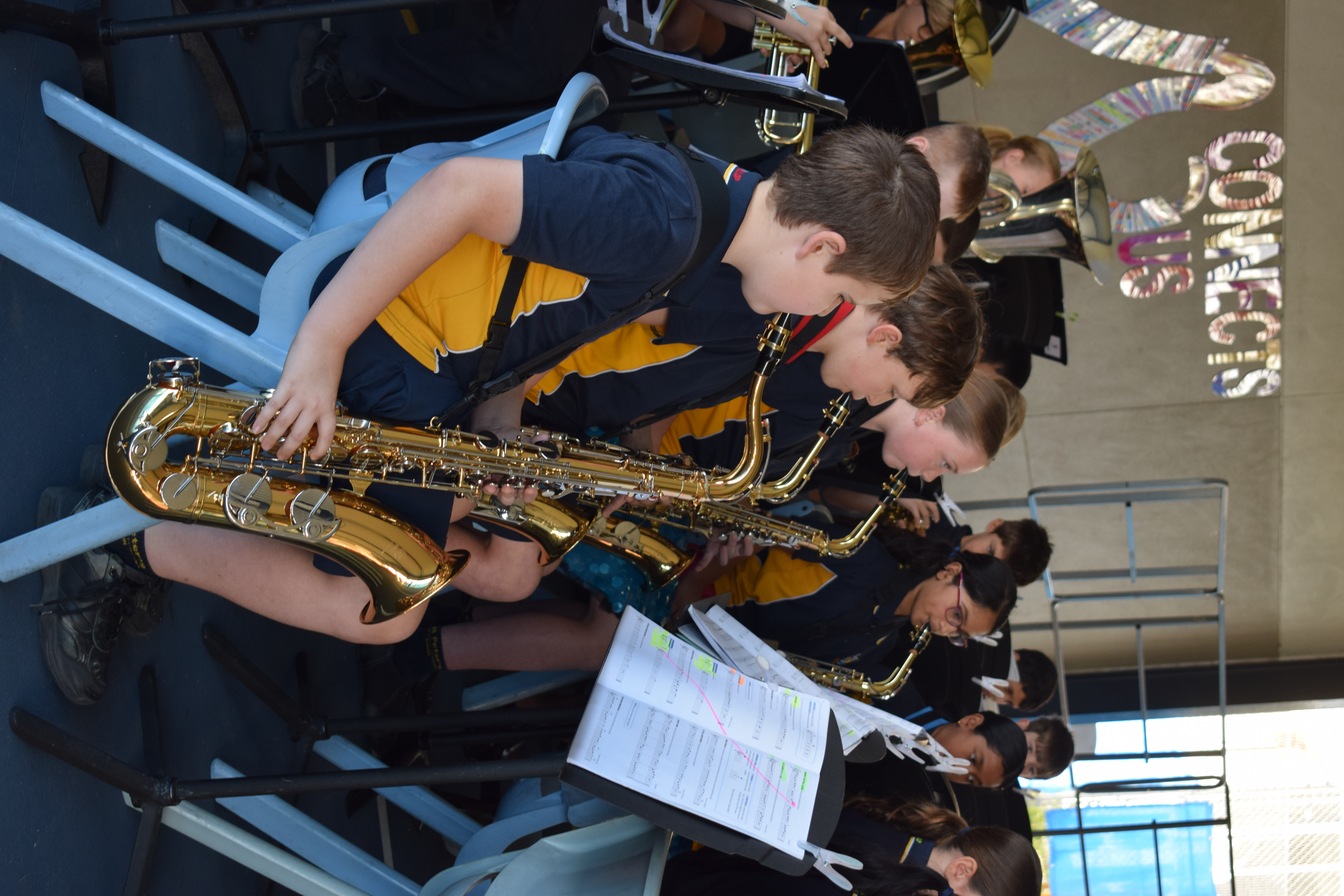 Students seated in rows playing saxophones during a school band rehearsal