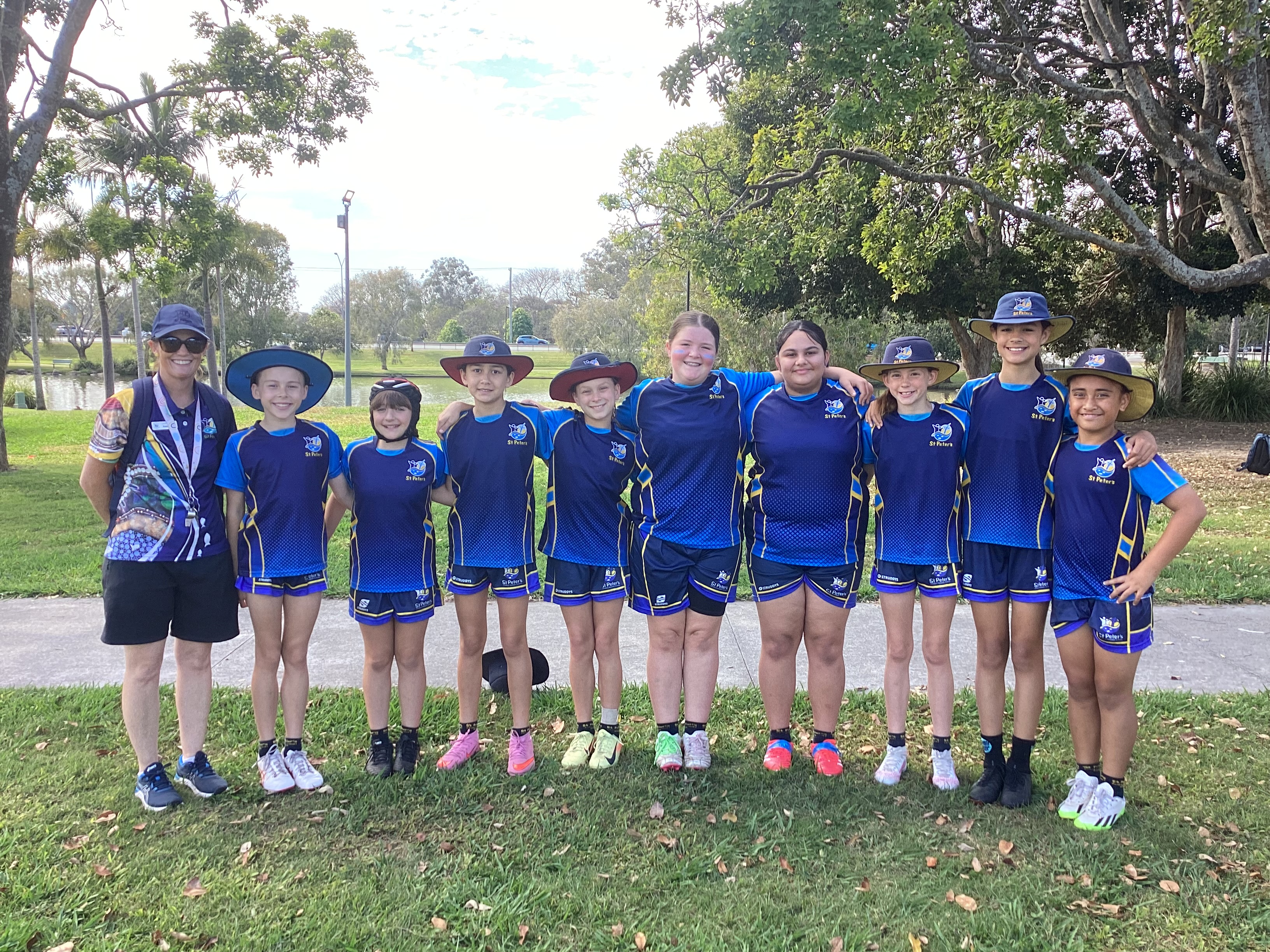 Group of students and an adult standing together outdoors wearing matching sports uniforms