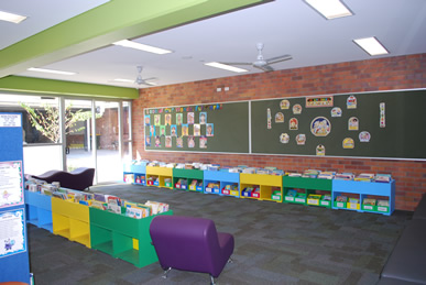 Classroom reading area with low bookshelves, wall displays, and seating