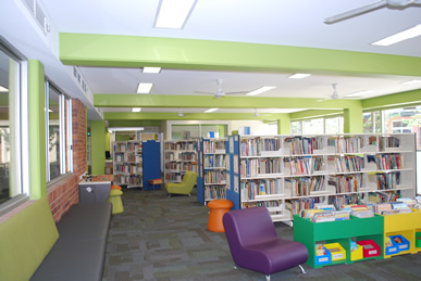 Library space with bookshelves, seating, and large windows